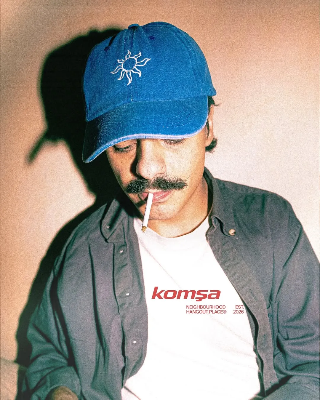 Guest wearing a Komša neighbourhood hangout place shirt and blue cap