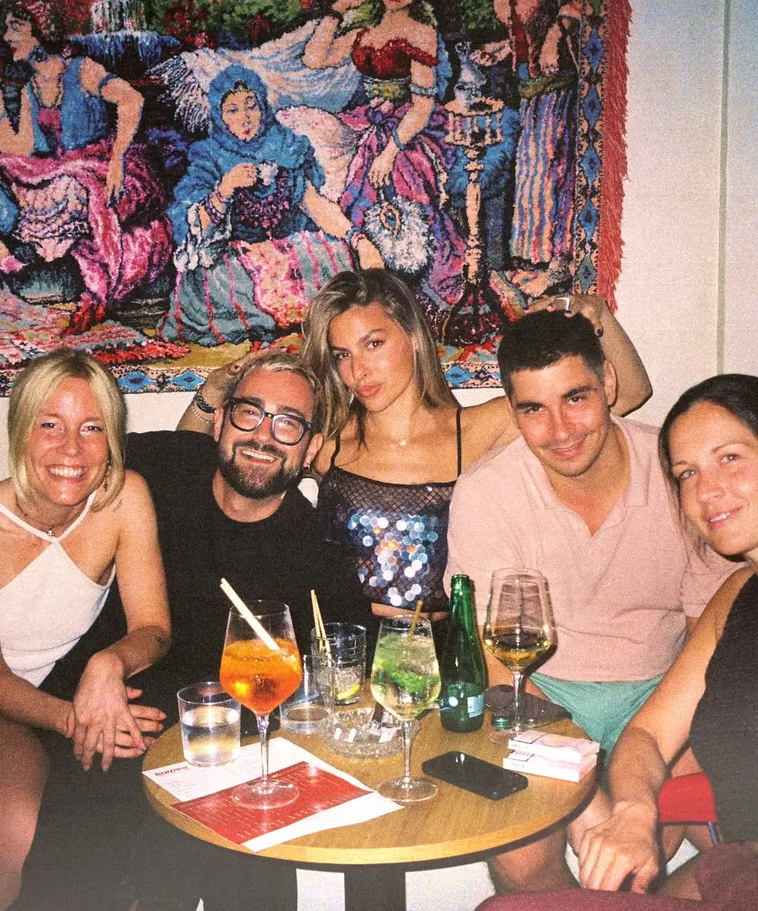 Friends gathered around a table with drinks at Komša