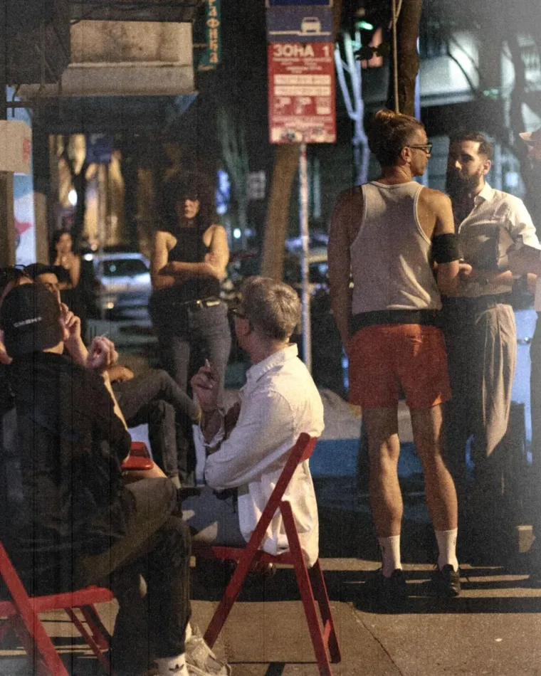 Guests on red chairs outside Komša, the street at night